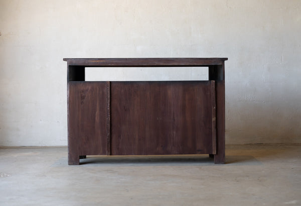Back of wooden sideboard cabinet against a plain wall.