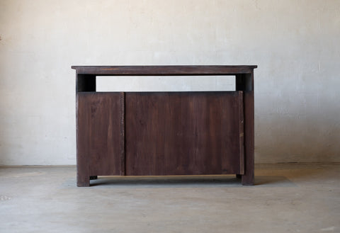 Back of wooden sideboard cabinet against a plain wall.