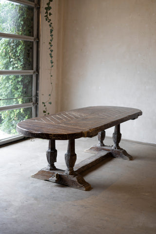Vintage wooden table in a room with large windows and a white wall.