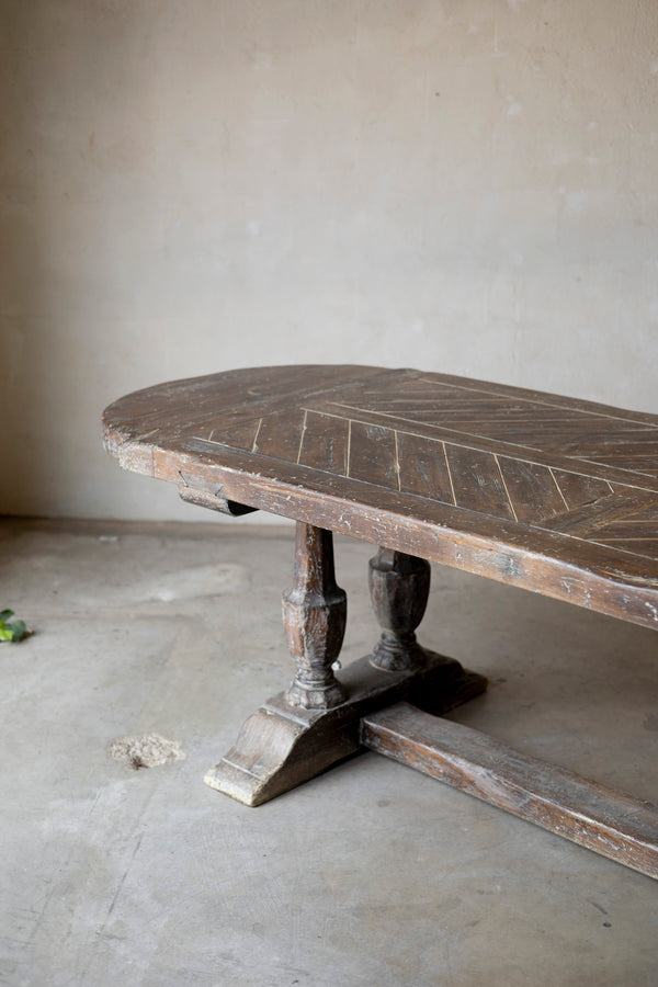 Wooden table with intricate carvings on a plain floor.