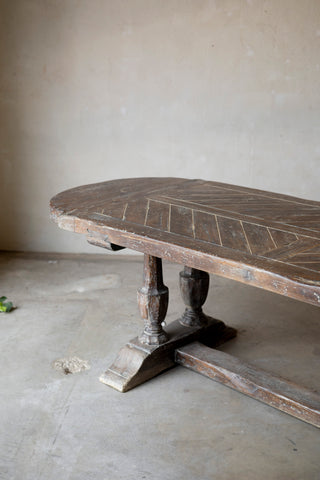 Wooden table with intricate carvings on a plain floor.