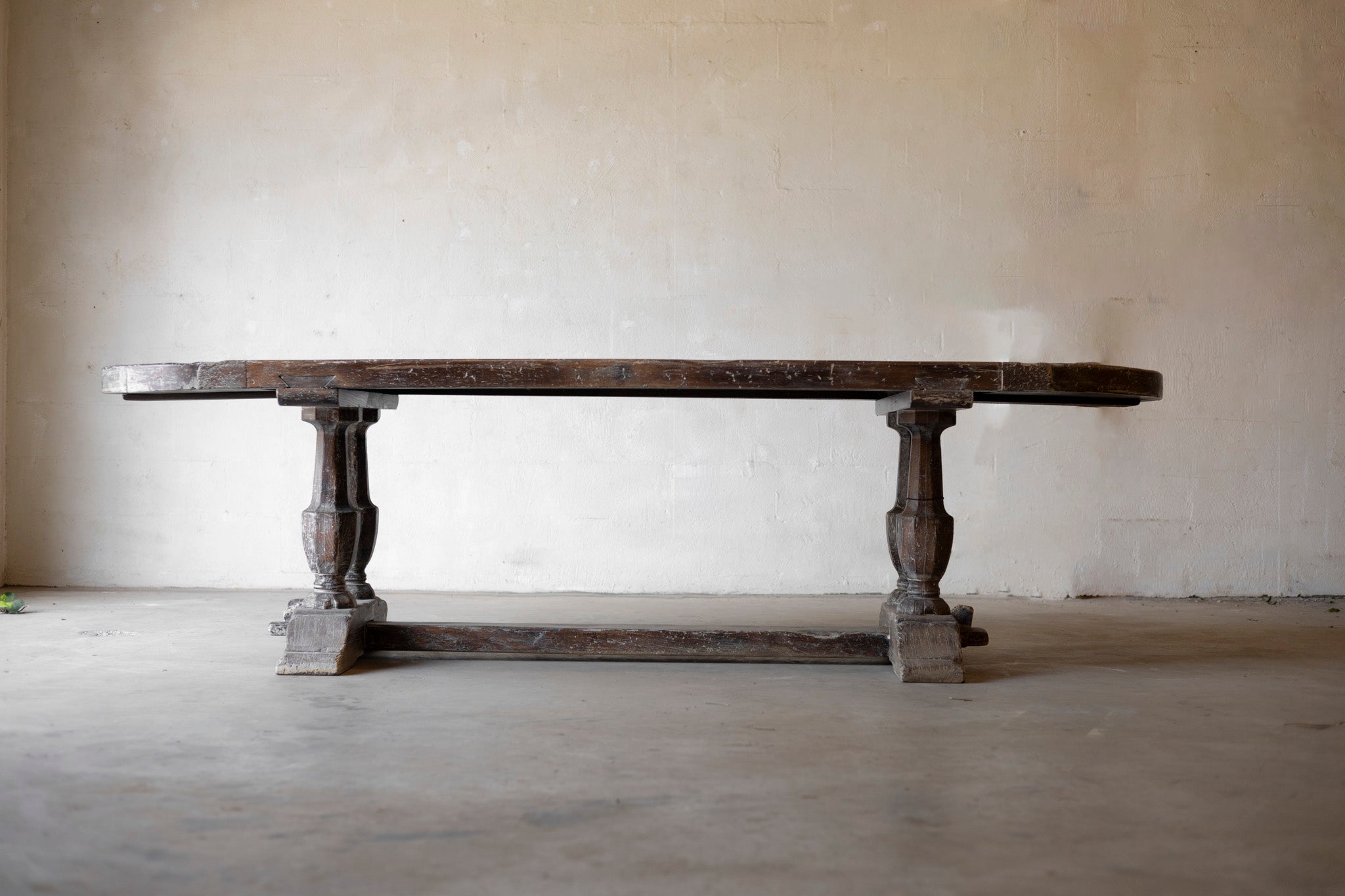 Large wooden table with a rustic design against a plain wall.