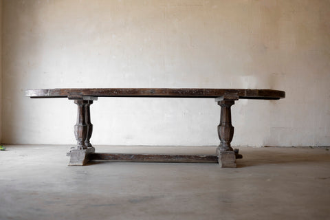 Large wooden table with a rustic design against a plain wall.