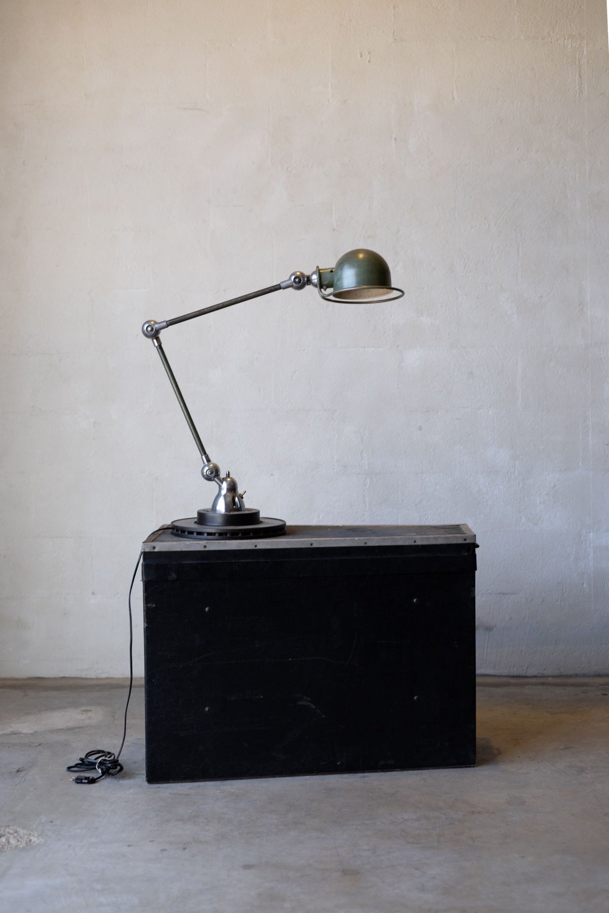 Vintage Jielde industrial desk lamp on a black metal cabinet against a plain wall. Main image