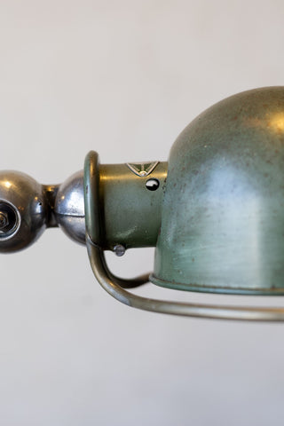 Close-up of a metal Jielde lamp with a sea green shade on a white background