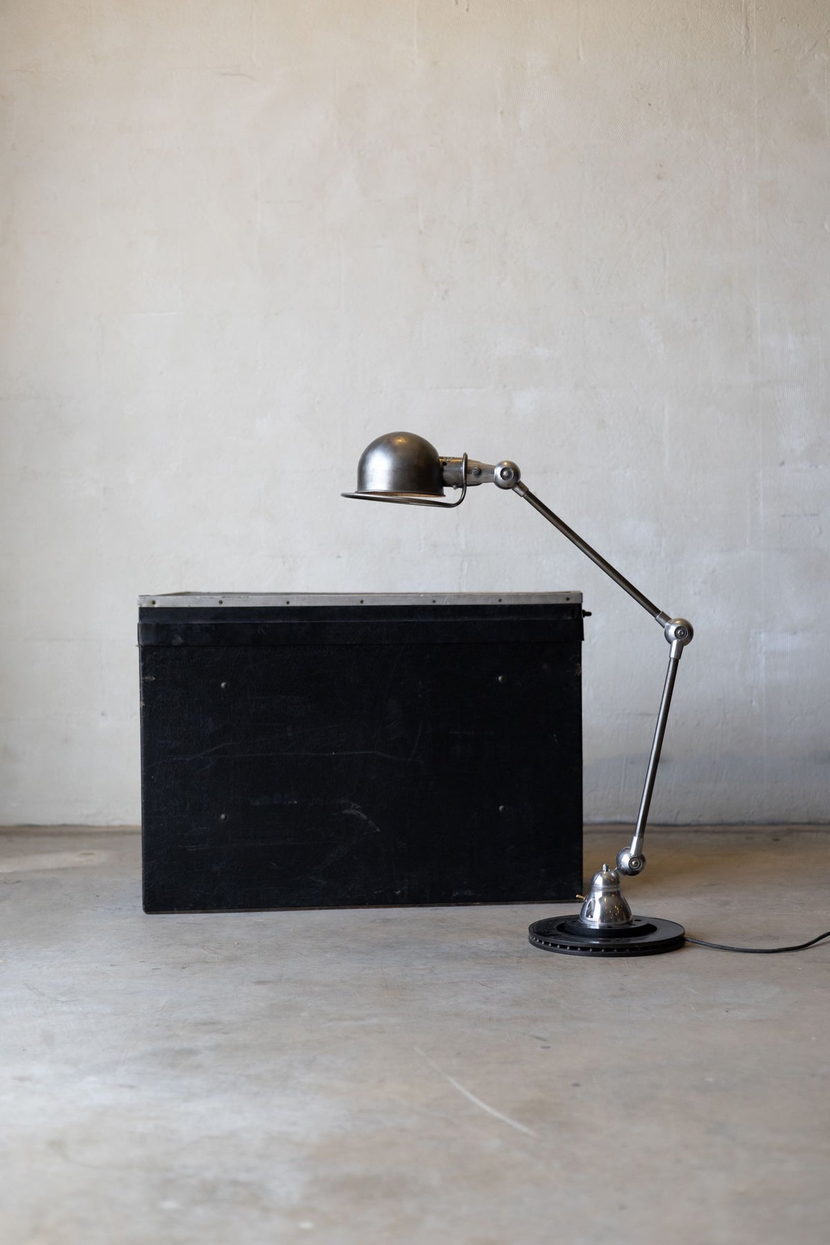 Vintage Jielde task lamp with long arm next to a black rectangular object on a plain background Main image