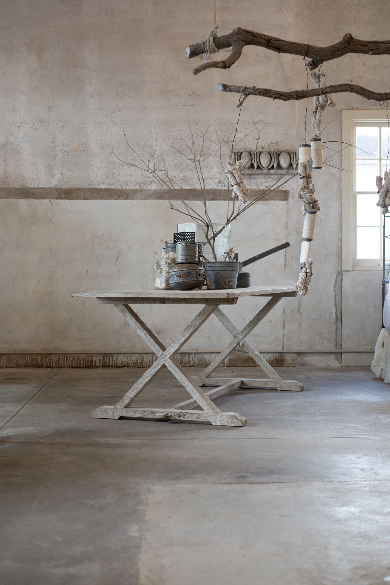 Rustic wooden table with decorative elements in a room with concrete floor and wall.