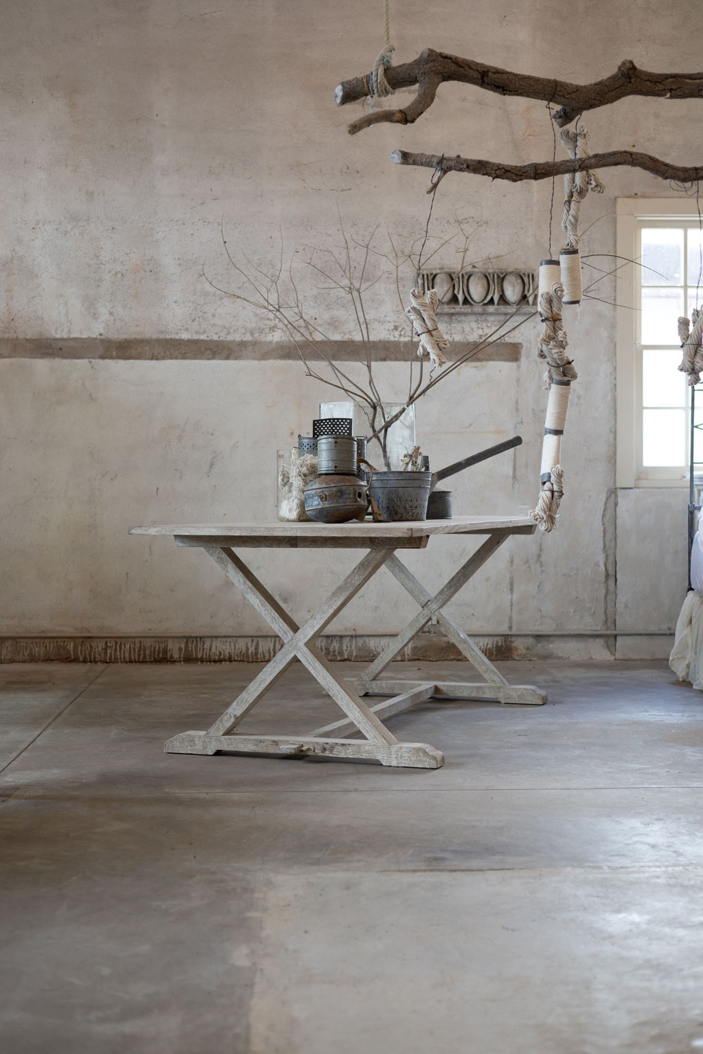 Rustic wooden table with decorative elements in a room with concrete floor and wall.