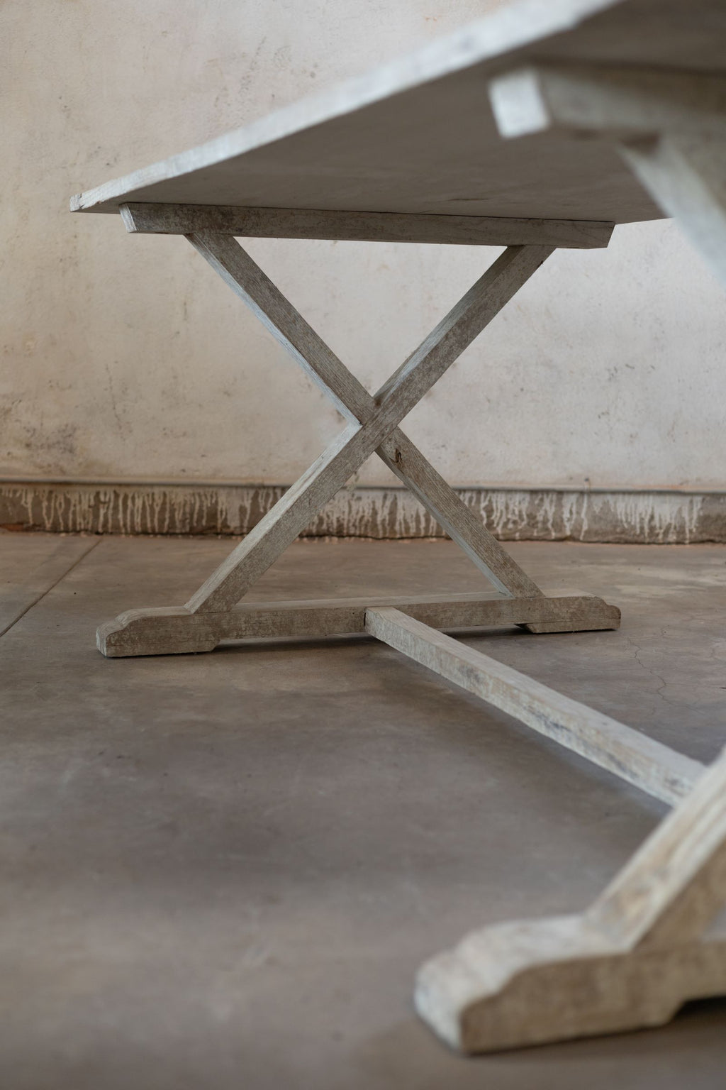 Bottom angle of wooden table with a rustic design on a concrete floor.