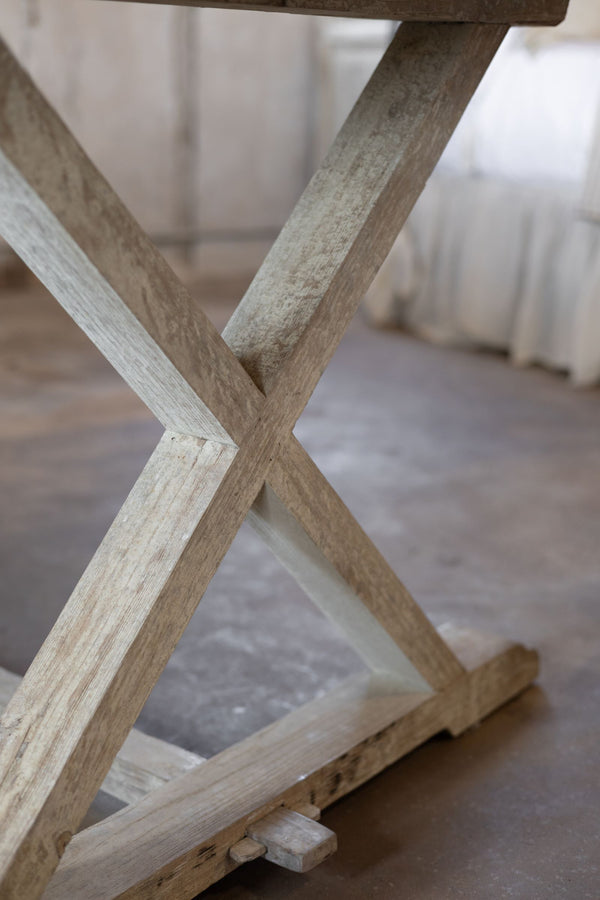 Close-up of a wooden X-shaped frame of trestle table on a blurred background