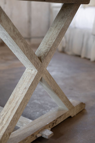Close-up of a wooden X-shaped frame of trestle table on a blurred background