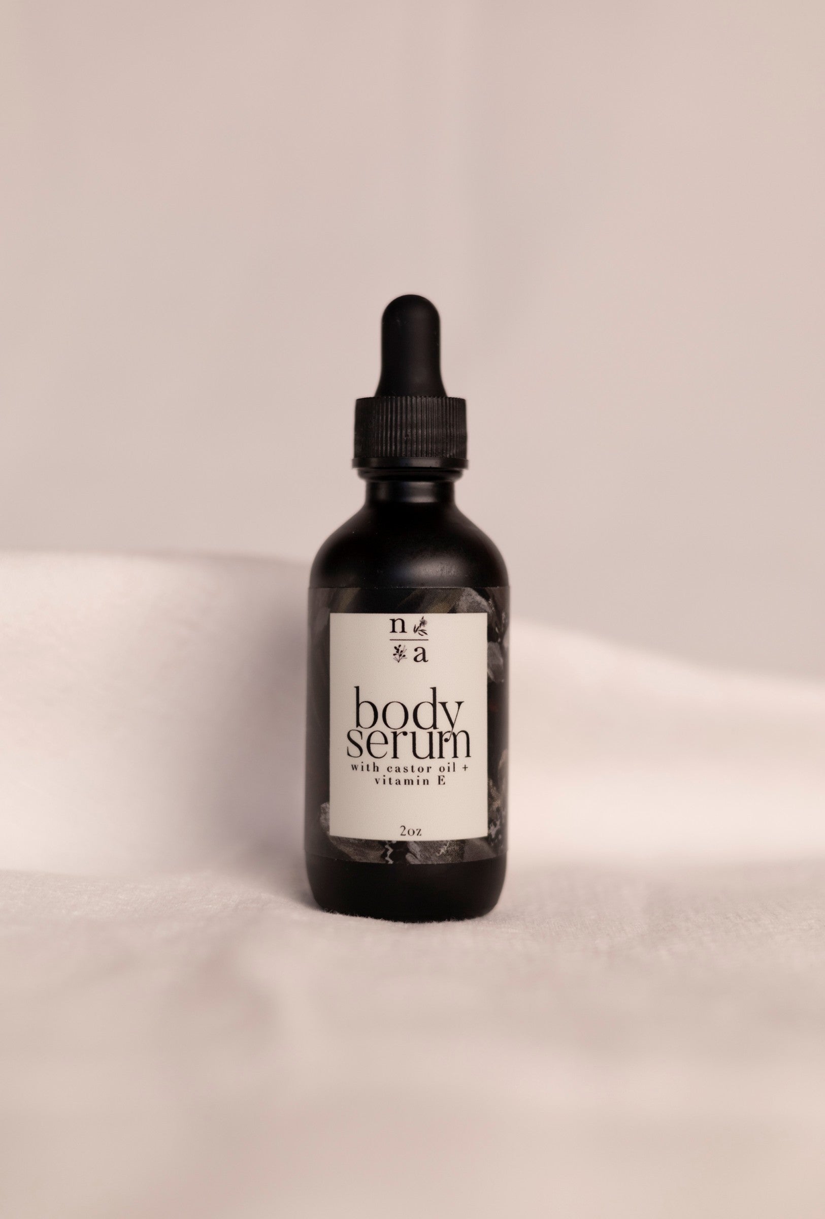Black bottle of anti-aging body serum with a dropper on a beige background.