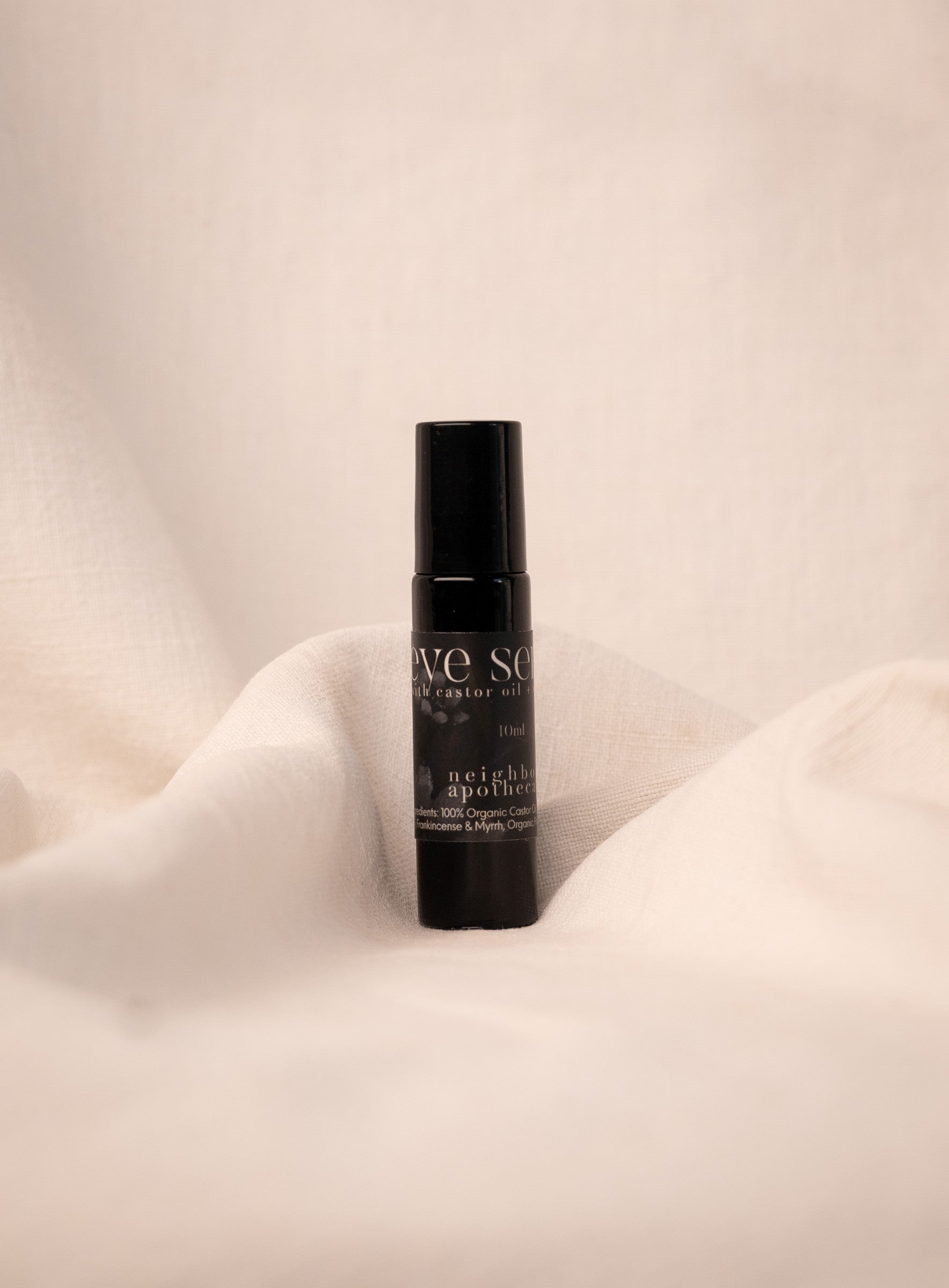 Black anti-aging eye serum bottle on a beige fabric background.