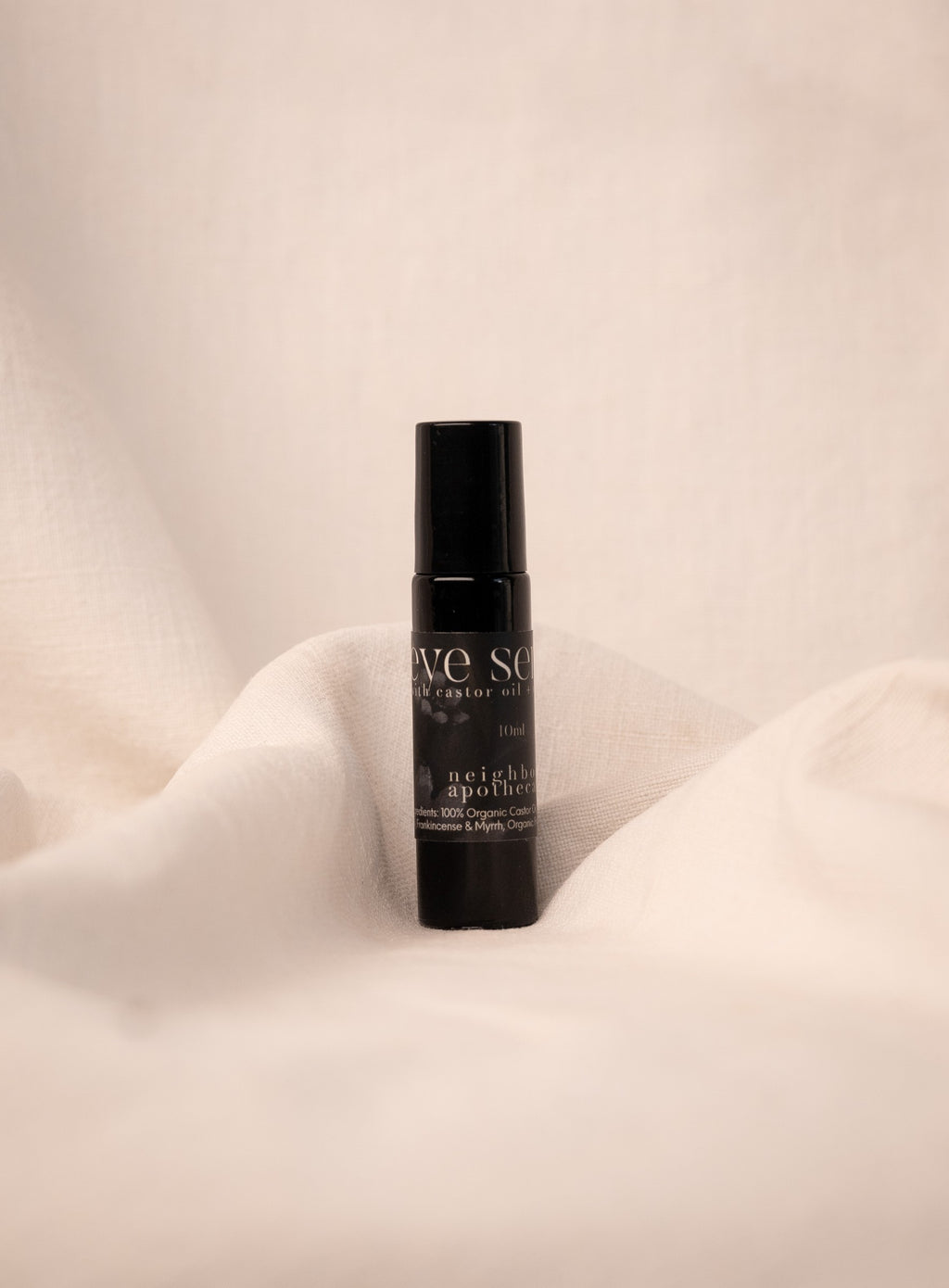 Black anti-aging eye serum bottle on a beige fabric background.