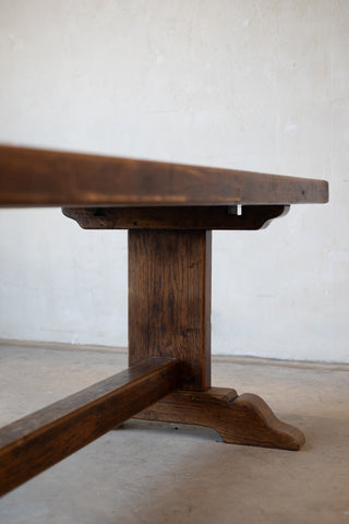 Vintage French oak dining table with a rustic design featuring double pedestal base on a plain background