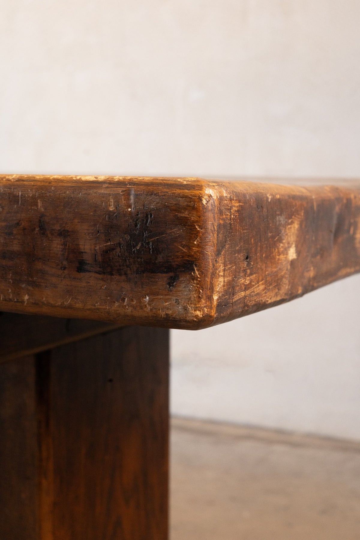 Close-up of a corner of a vintage French oak dining table with a white background