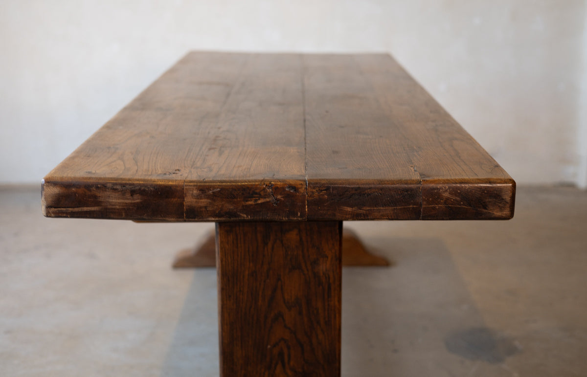 Image of a top of vintage French oak dining table in front of a plain background. 