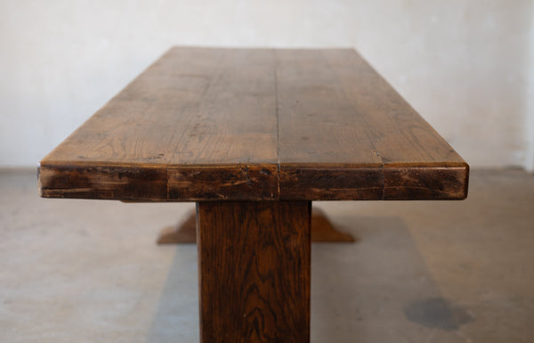 Image of a top of vintage French oak dining table in front of a plain background. 