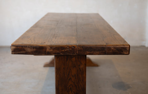 Image of a top of vintage French oak dining table in front of a plain background. 