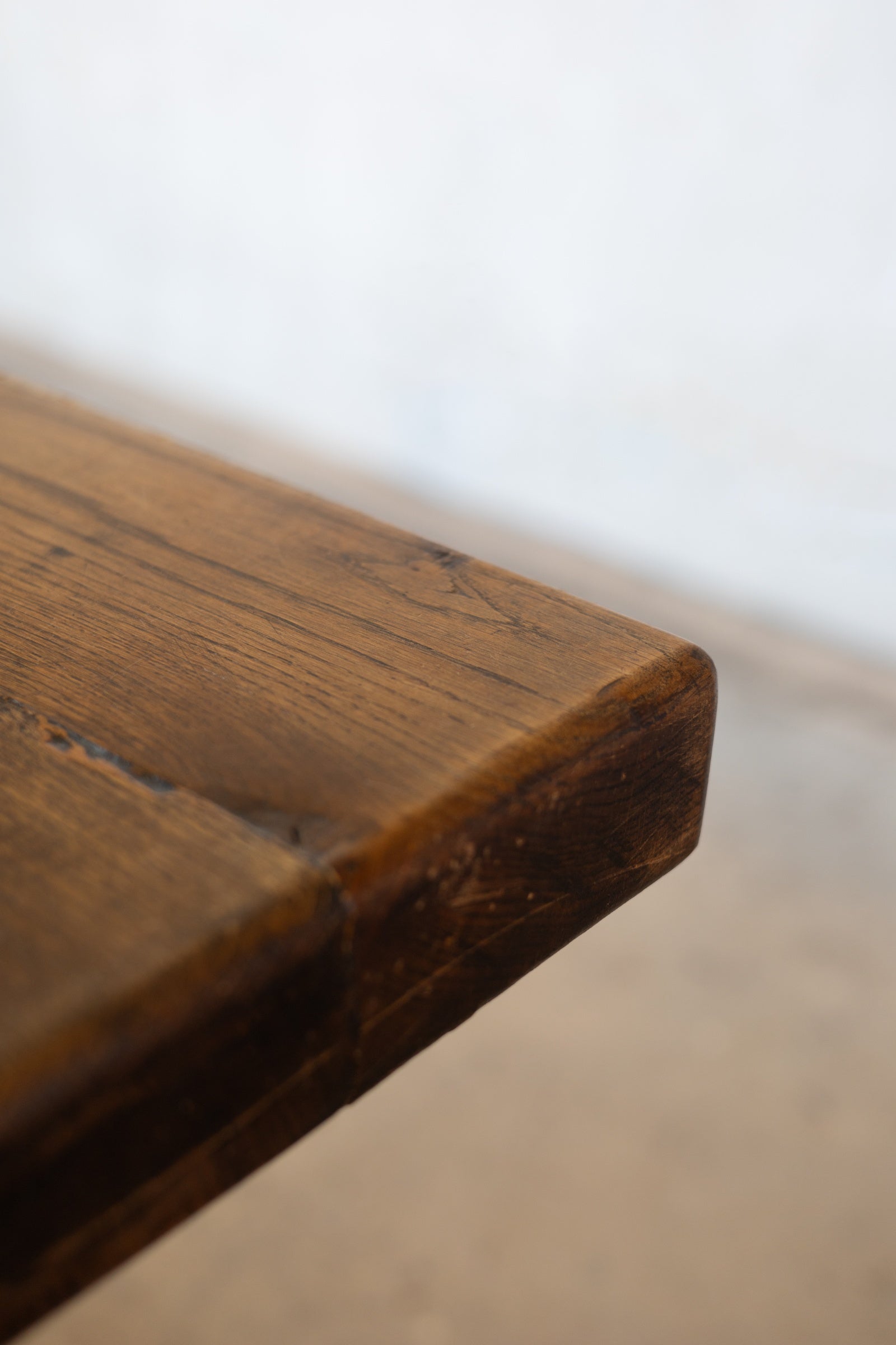 Close up of corner of a wooden table showing the wood grain and rounded edges. 
