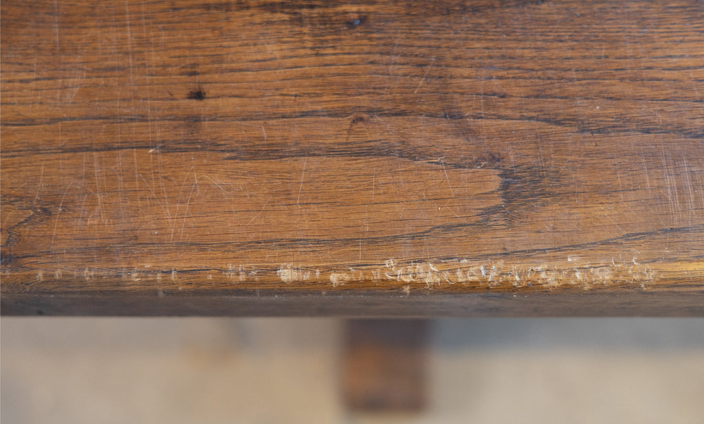 Close-up of a wooden surface of a table with visible wear and tear.