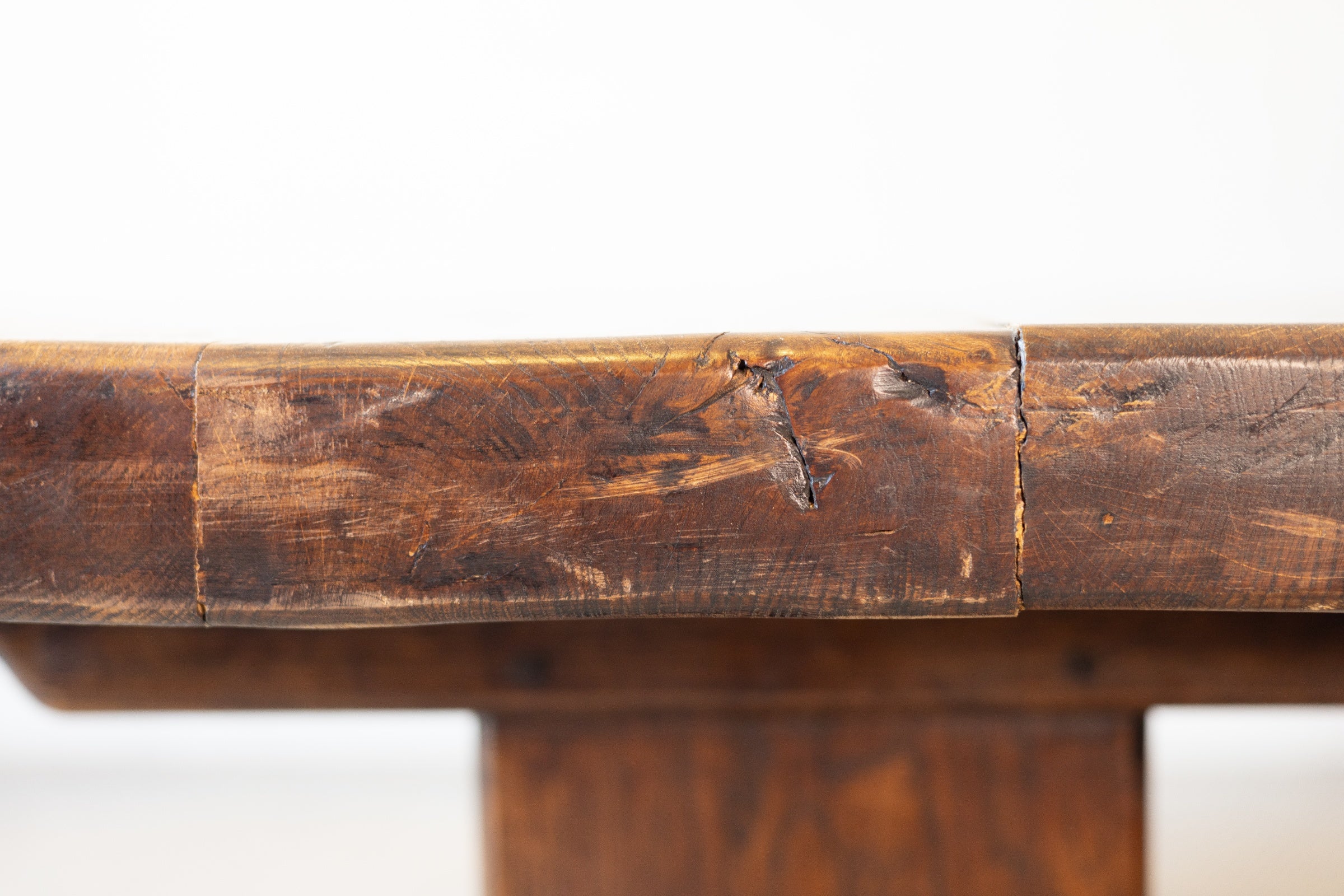 Close-up of edge of a vintage French oak dining table with a white background