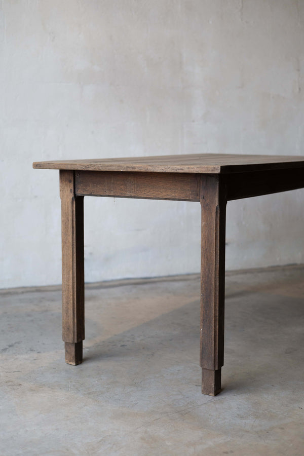 Corner shot of an oak farm table with a rustic finish and mortise and tenon joints.