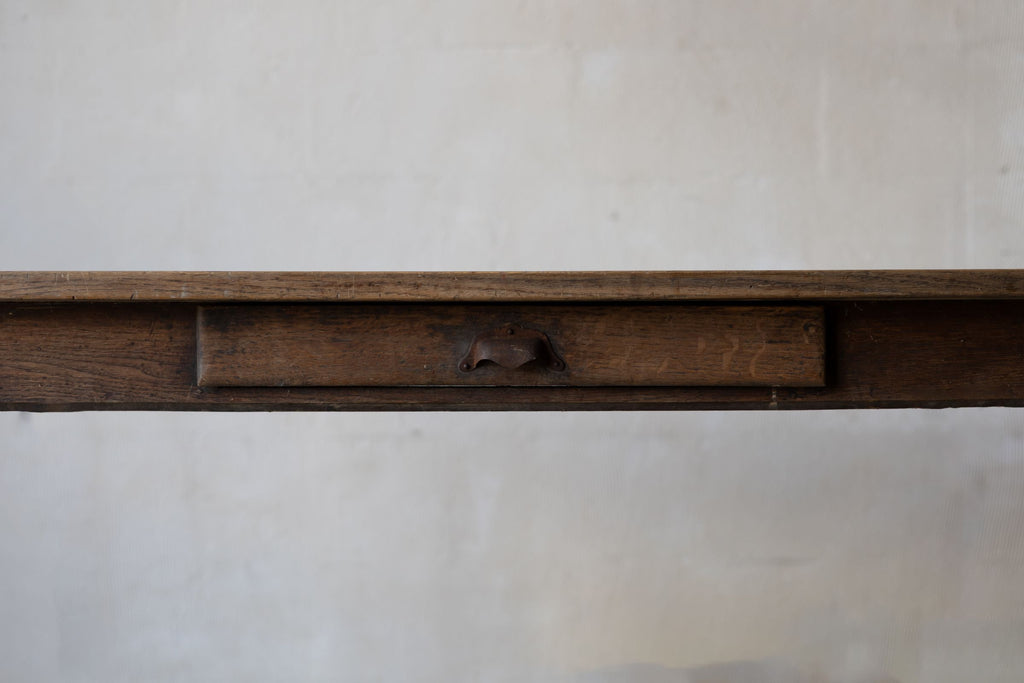 Close up image of a thin tabletop, and a drawer with a metal handle.