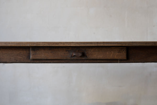 Close up image of a thin tabletop, and a drawer with a metal handle.
