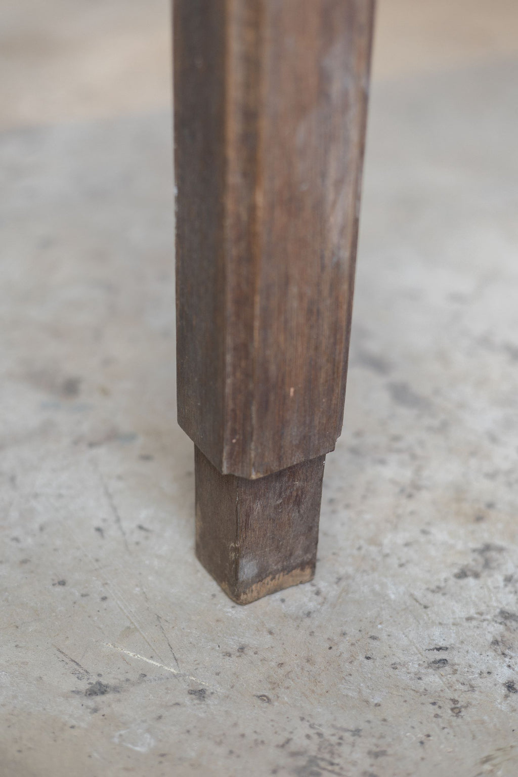 Close up image of oak farm table leg with a rustic finish, showing natural wear and aging.