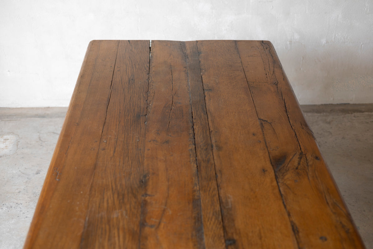 Wooden table with a rustic appearance against a plain wall.