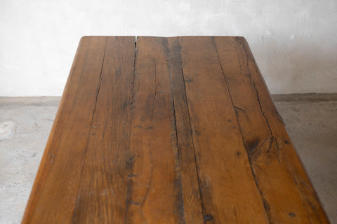 Wooden table with a rustic appearance against a plain wall.