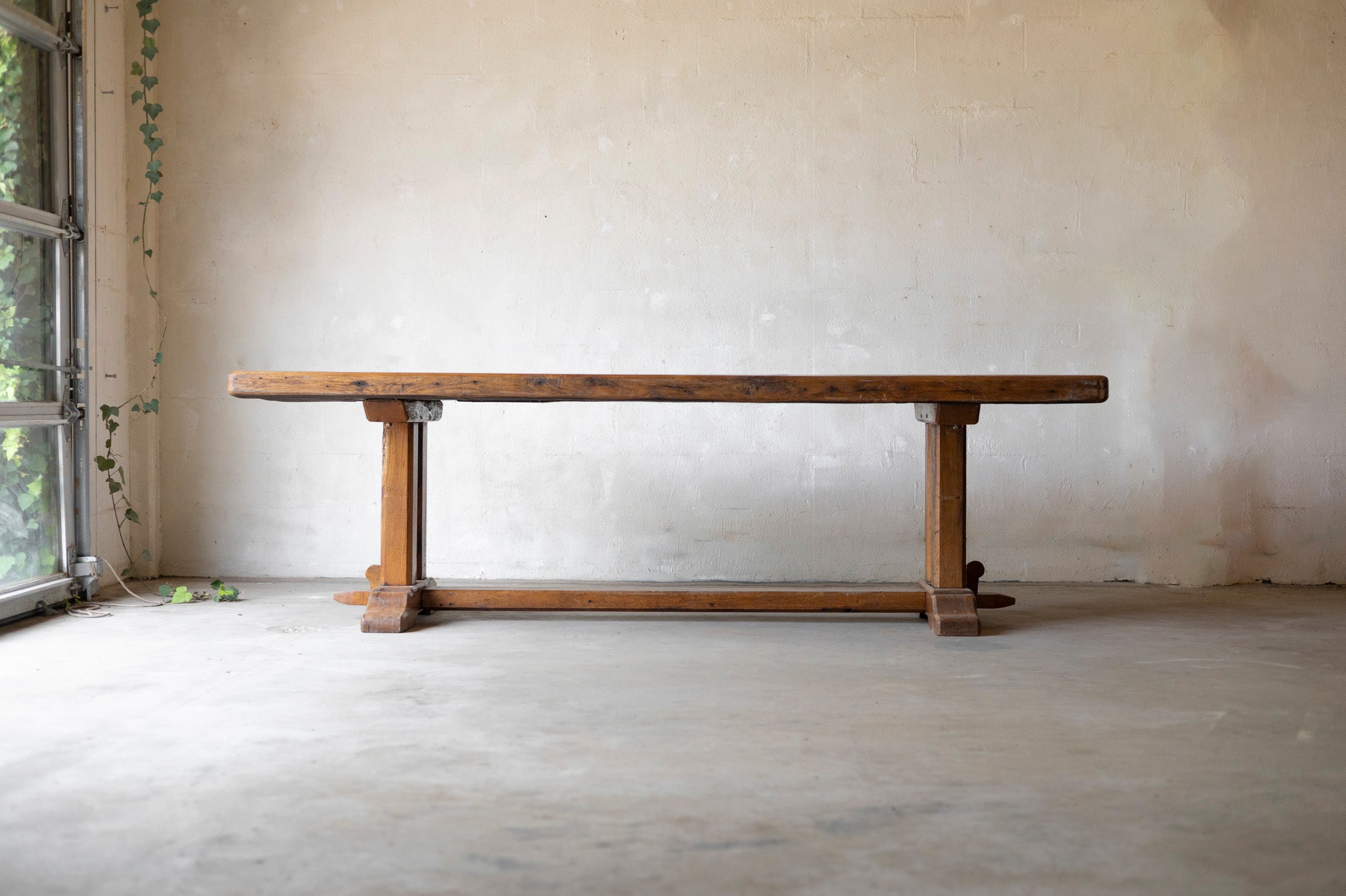 Wooden table in a minimalistic room with a light-colored wall and floor.
