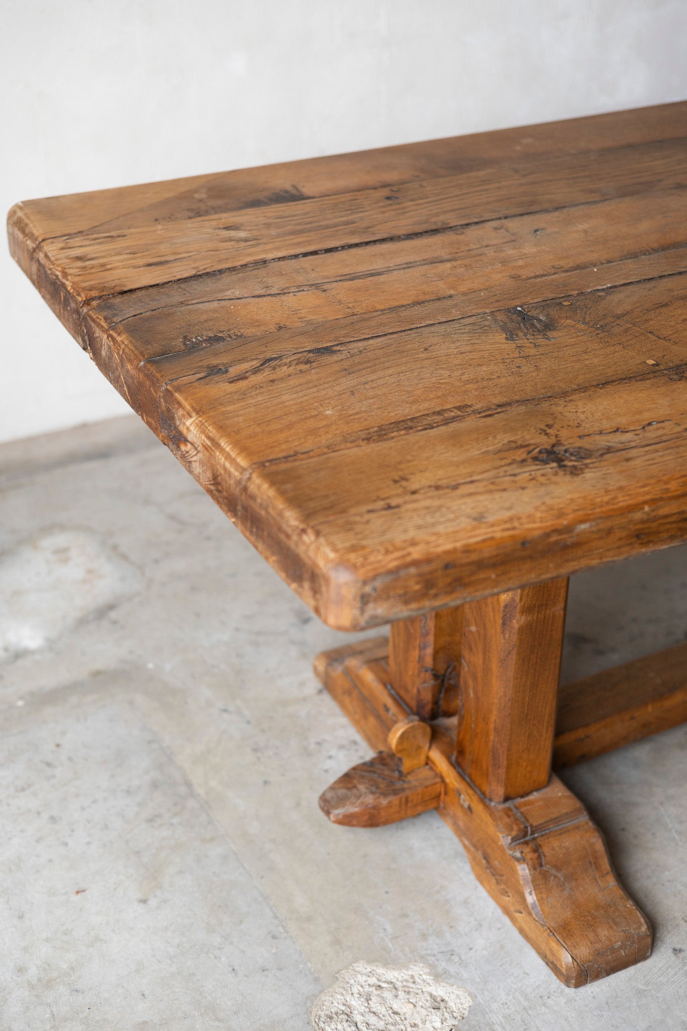 Wooden table with rustic design on a light gray floor