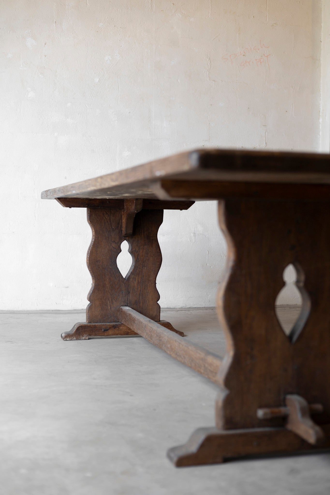 Wooden table with decorative legs on a light gray floor and white wall background