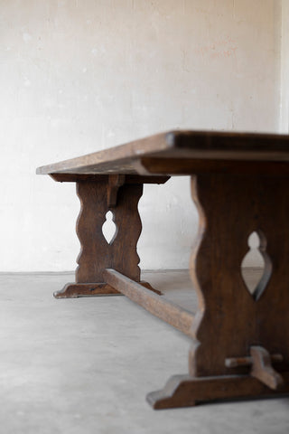 Wooden table with decorative legs on a light gray floor and white wall background