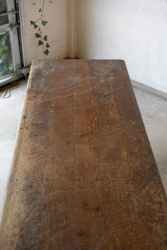 Old wooden table in a room with a window and plant