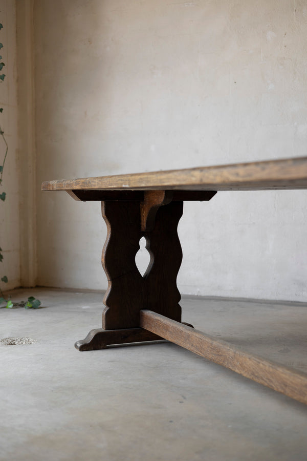 Wooden table with a dark base against a plain wall