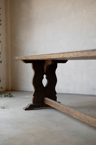 Wooden table with a dark base against a plain wall