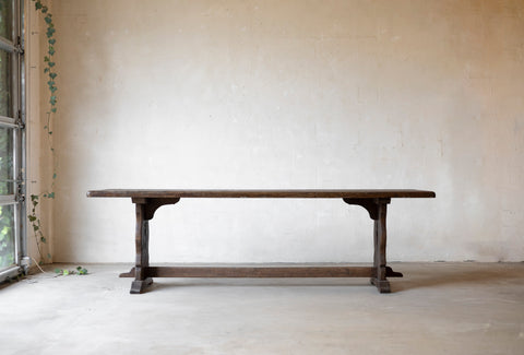 Wooden table against a plain wall with a window on the left.