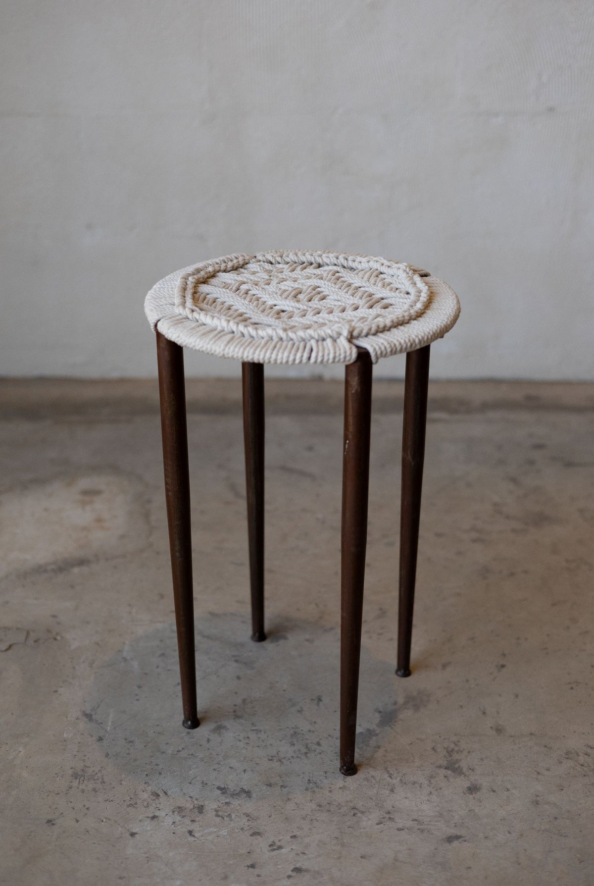 Iron stool with four legs and an intricately woven cotton seat. Main image