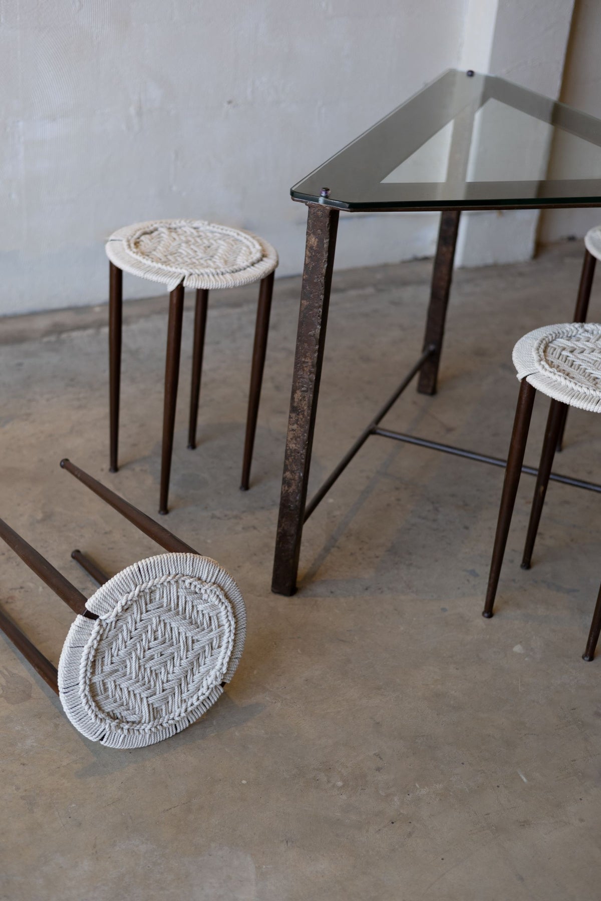 Stools around glass and iron table with one stool tipped over.