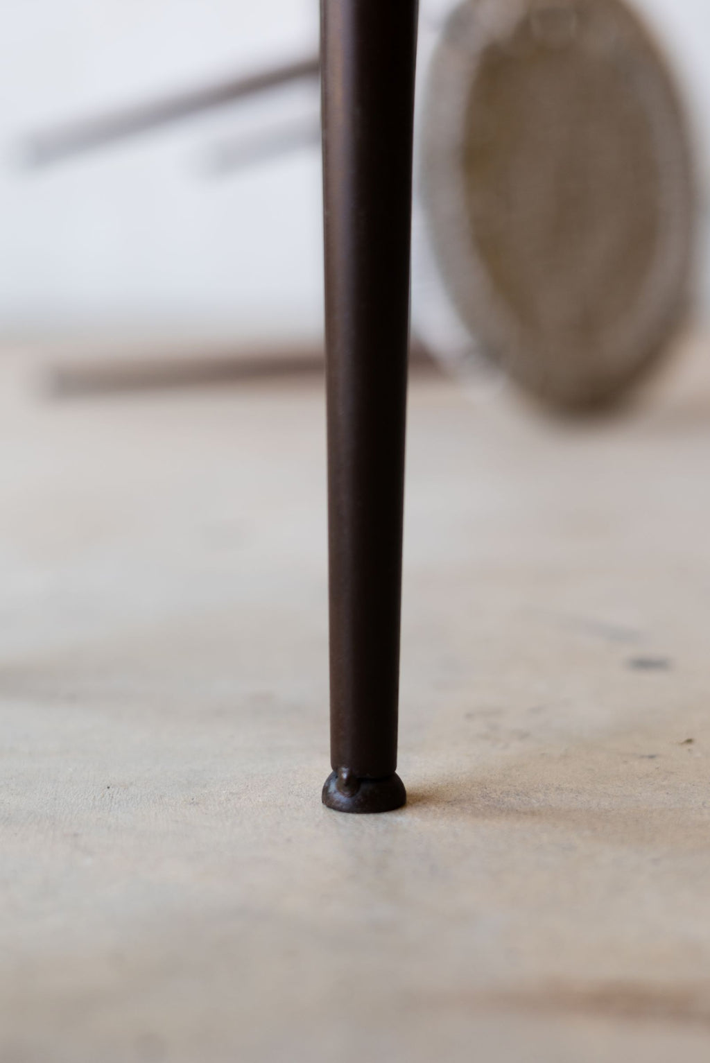 Close up of thin iron leg of stool.