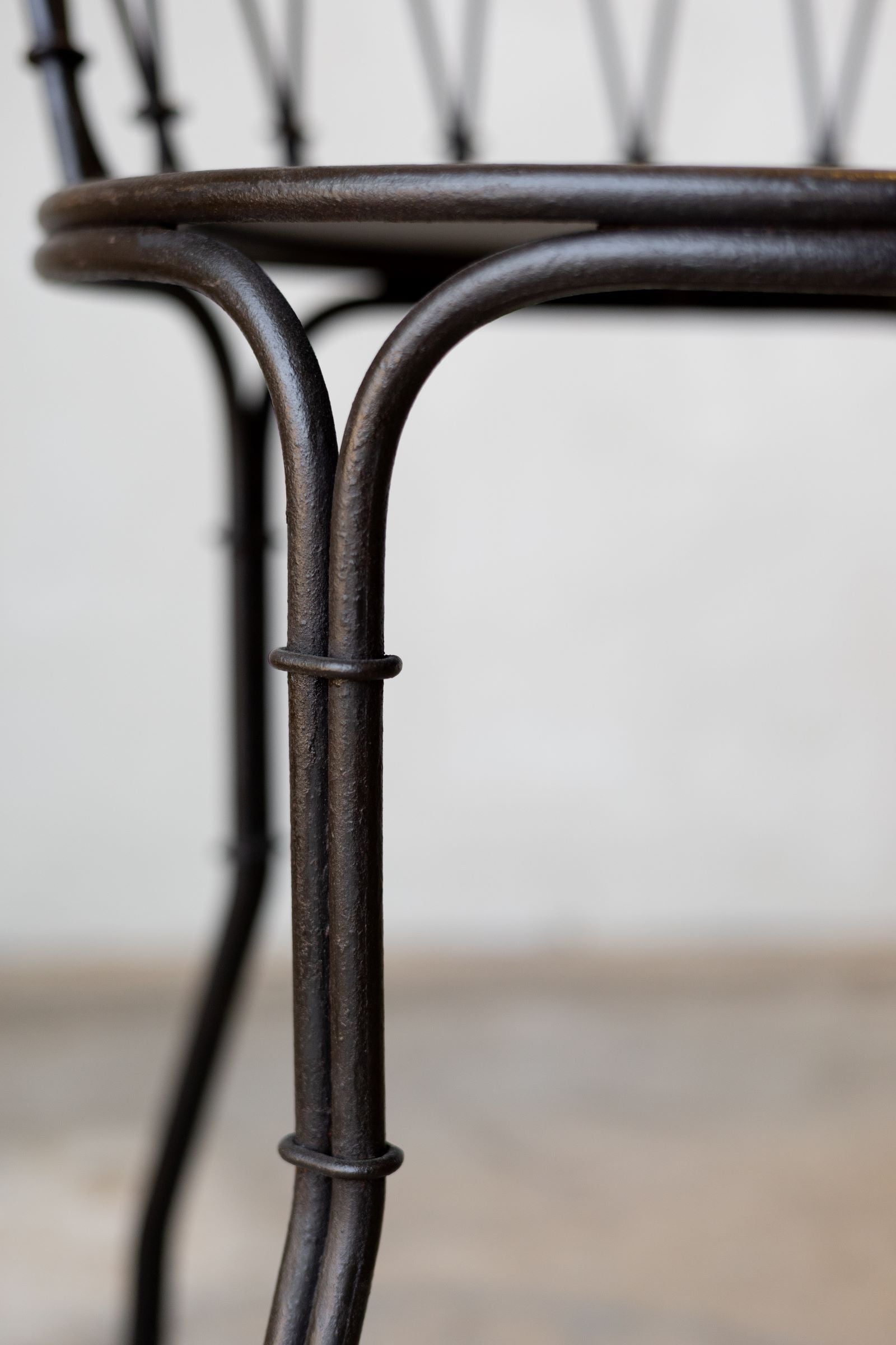 Close up of leg and seat of iron French bistro style dining. 