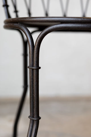 Close up of leg and seat of iron French bistro style dining. 