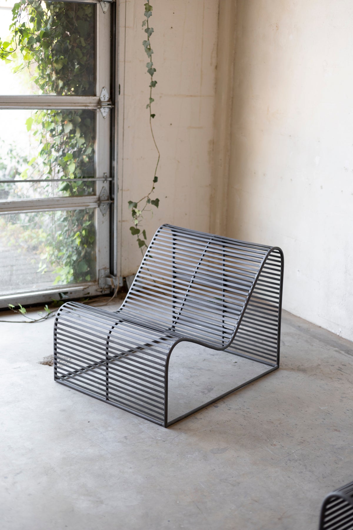 Modern metal chair in a room with a window and plants Main image