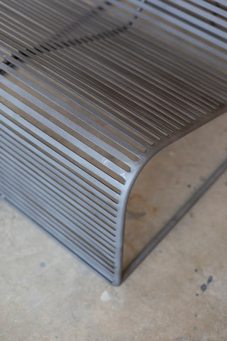 Close-up of a metal chair with a curved backrest on a plain background