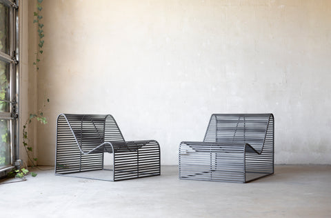 Modern wireframe chairs in a minimalistic room with a window and plant.