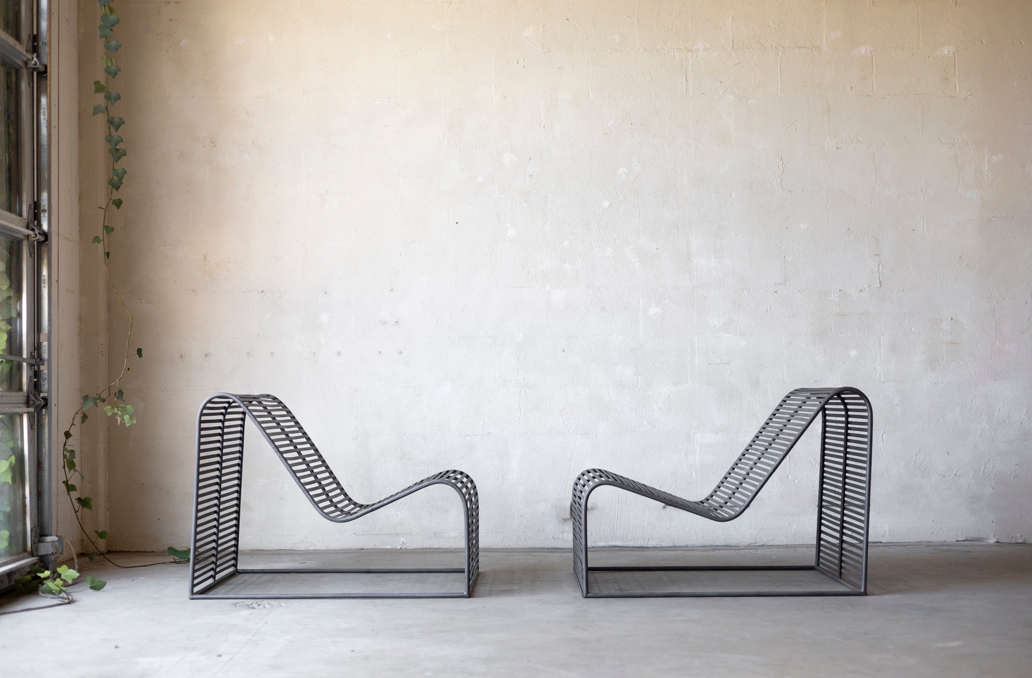 Two wireframe chairs against a plain wall with a window on the left.