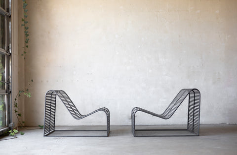 Two wireframe chairs against a plain wall with a window on the left.